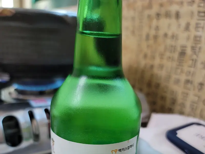 테이블 위 가스레인지와 녹색 소주병