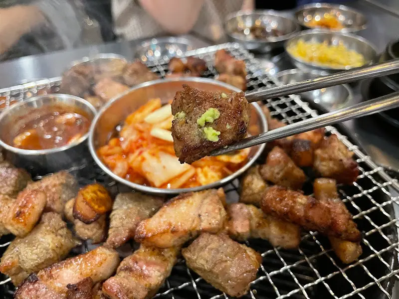 잘 구워진 삼겹살 한 점을 젓가락으로 집어 올린 모습