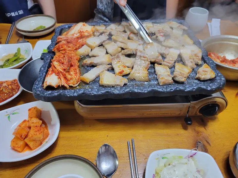 불판 위에서 삼겹살과 김치가 함께 구워지고 있는 모습