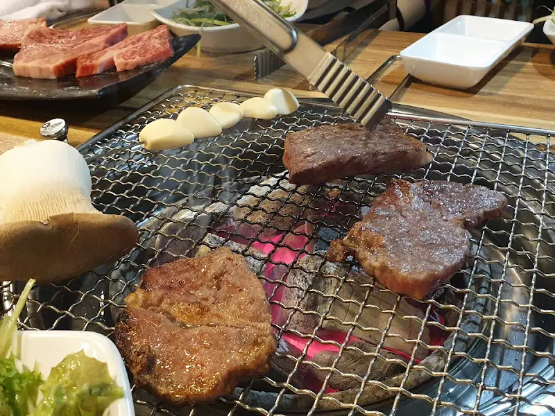 숯불 위에서 맛있게 구워지고 있는 소고기와 버섯, 마늘의 모습