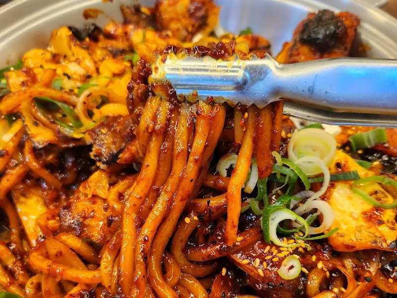 집게로 아구직화불고기 면발을 들어올리는 모습