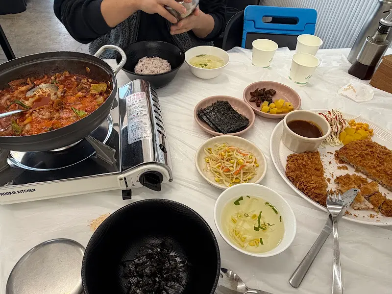 테이블 위에 차려진 낙지짜글이, 돈까스, 각종 반찬들
