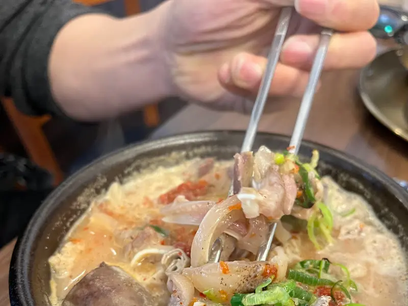 젓가락으로 들어올린 항정수육국밥 속 항정살 수육