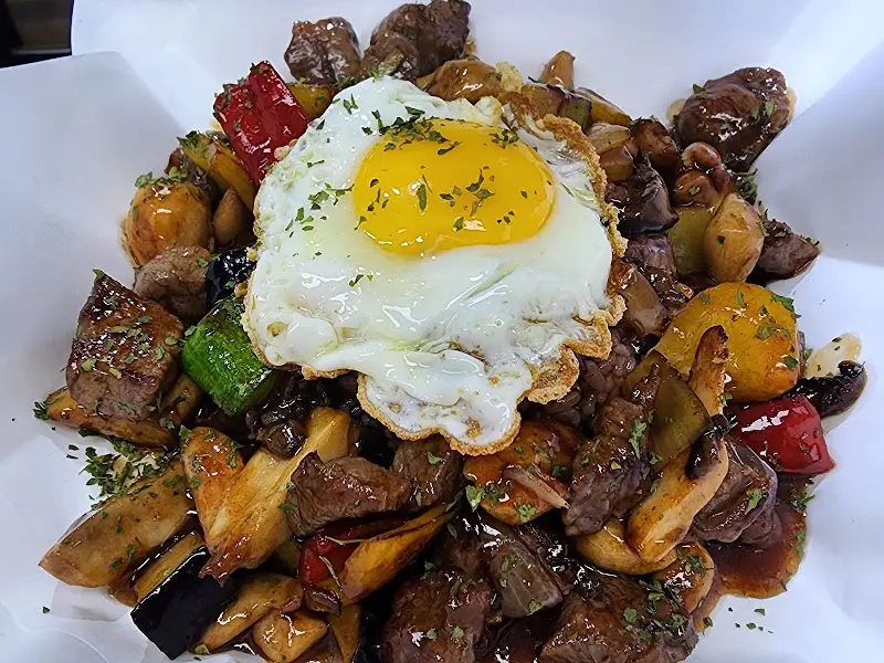 찹스테이크 덮밥 위에 올려진 반숙 계란을 클로즈업한 모습