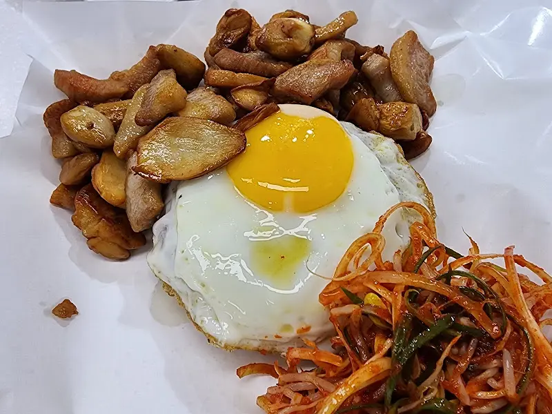 항정살 덮밥의 모습. 노릇하게 구워진 항정살과 파채, 콩나물 무침이 조화롭게 담겨 있다.