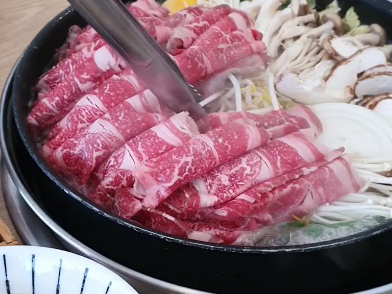 선홍빛 소고기와 싱싱한 채소가 가득한 스키야키 냄비