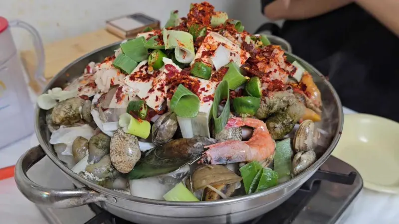 해물된장찌개가 끓기 전, 냄비 안에는 신선한 해산물과 야채, 두부가 가득 담겨 있다.