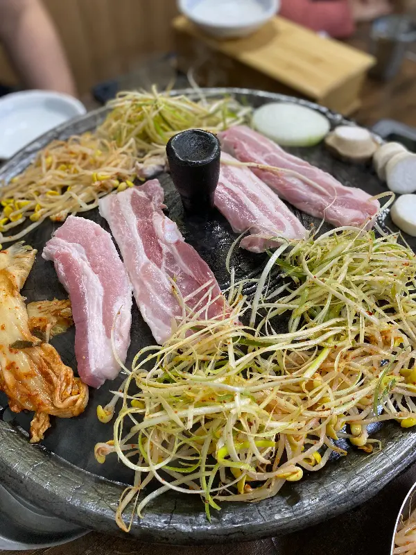 삼겹살과 김치, 콩나물을 함께 구워 쌈을 싸 먹는 모습