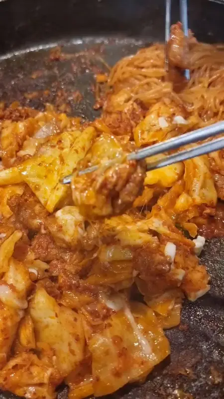 젓가락으로 닭갈비를 집어 올리는 모습