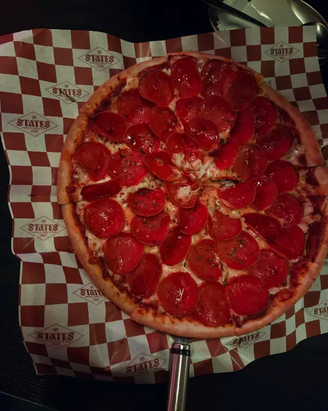 스테이츠 페퍼로니 피자: 얇은 도우 위에 페퍼로니가 가득 올려져 있다.