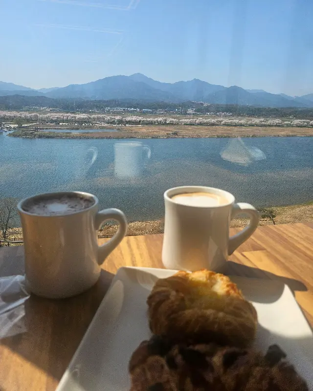 창밖 풍경을 바라보며 커피와 디저트를 즐기는 모습