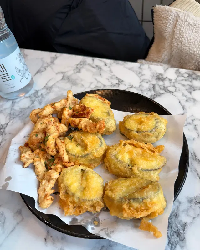 테이블 위에 놓인 반반 튀김 접시. 튀김옷의 바삭함이 생생하게 느껴진다.