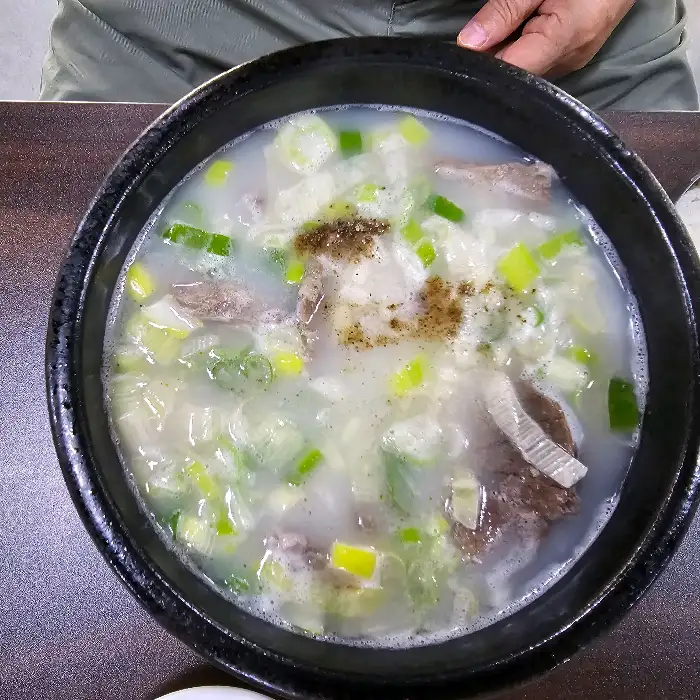 하얀 국물의 곰탕과 밥, 김치, 깍두기가 함께 나온 모습