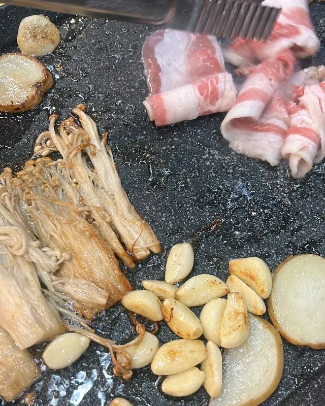 불판 위에서 익어가는 대패삼겹살, 버섯, 마늘