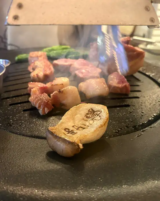숯불 위에서 맛있게 구워지고 있는 다양한 돼지고기 부위