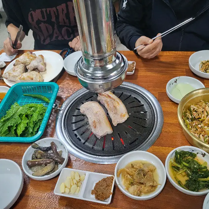 불판 위에서 구워지고 있는 돼지고기와 여러 반찬들