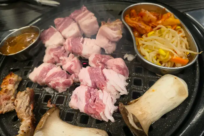 두툼한 삼겹살이 불판 위에서 익어가고 있는 모습