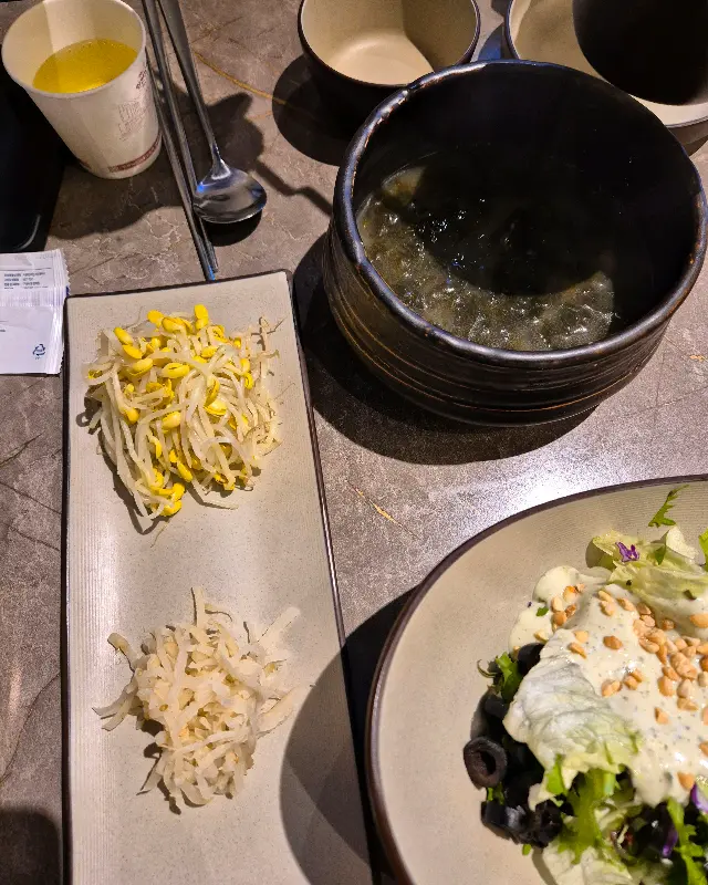 깔끔하게 차려진 밑반찬. 샐러드, 콩나물, 무생채 등 다양한 메뉴가 제공된다.