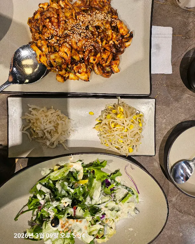 윤기가 자르르 흐르는 쭈꾸미 볶음과 샐러드, 콩나물의 조화. 매콤한 쭈꾸미와 아삭한 콩나물이 환상적인 궁합을 자랑한다.