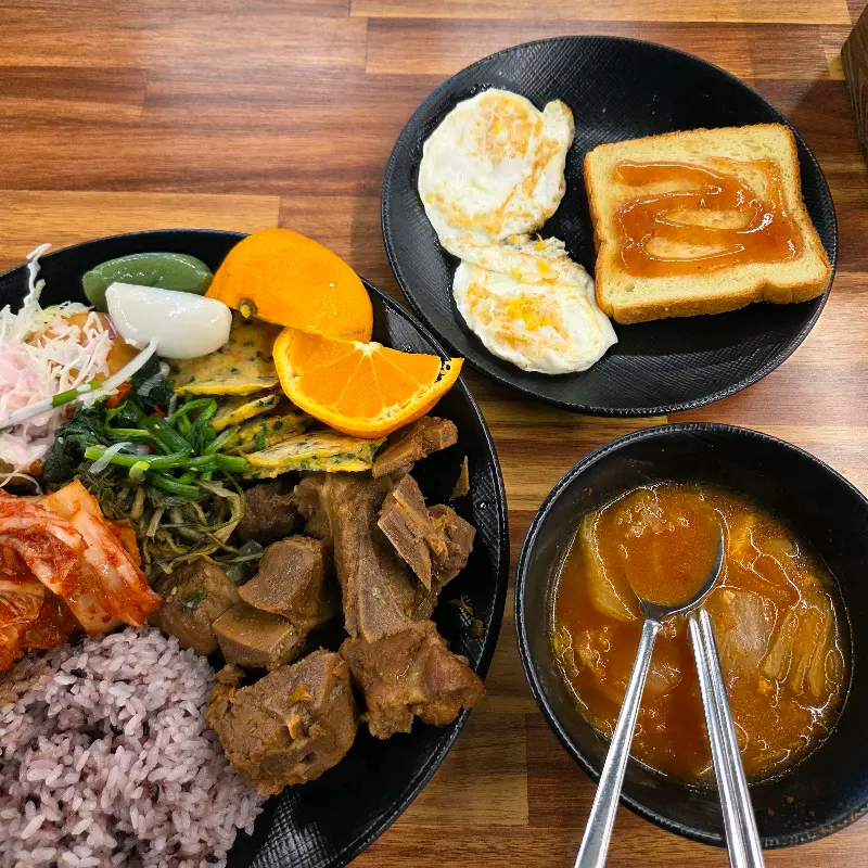 푸짐하게 차려진 한 상. 토스트와 계란후라이, 다양한 반찬이 눈길을 사로잡는다.