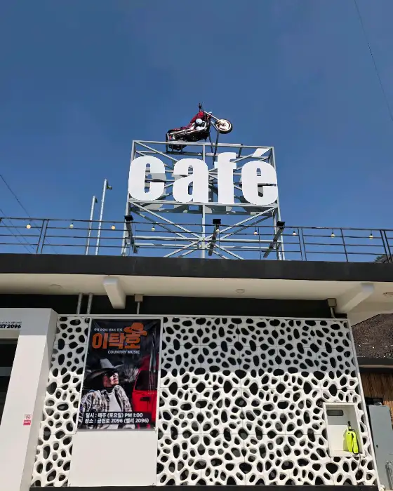 카페 건물 외관의 'cafe' 간판과 오토바이 조형물