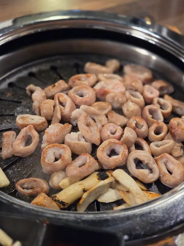 불판 위에서 구워진 막창과 떡, 버섯의 모습