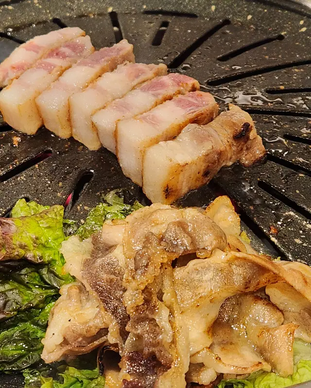 불판 위에서 맛있게 익어가는 삼겹살과 우삼겹