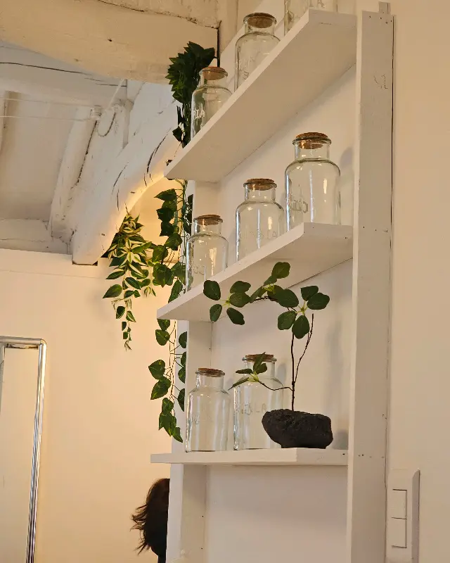 카페 내부의 모습. 흰색 벽과 나무 선반, 그리고 아기자기한 소품들이 조화롭게 어우러져 있다.