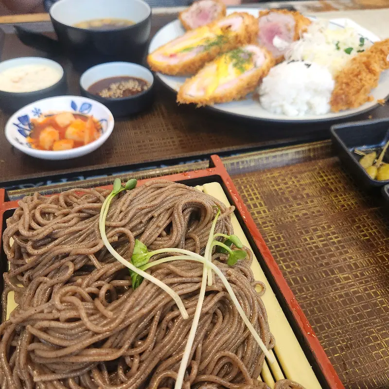 돈까스, 냉모밀, 샐러드, 반찬이 정갈하게 담긴 모습