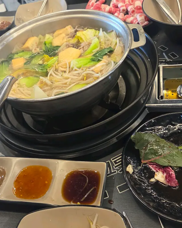 테이블 위에 놓인 샤브샤브 냄비와 소스, 접시