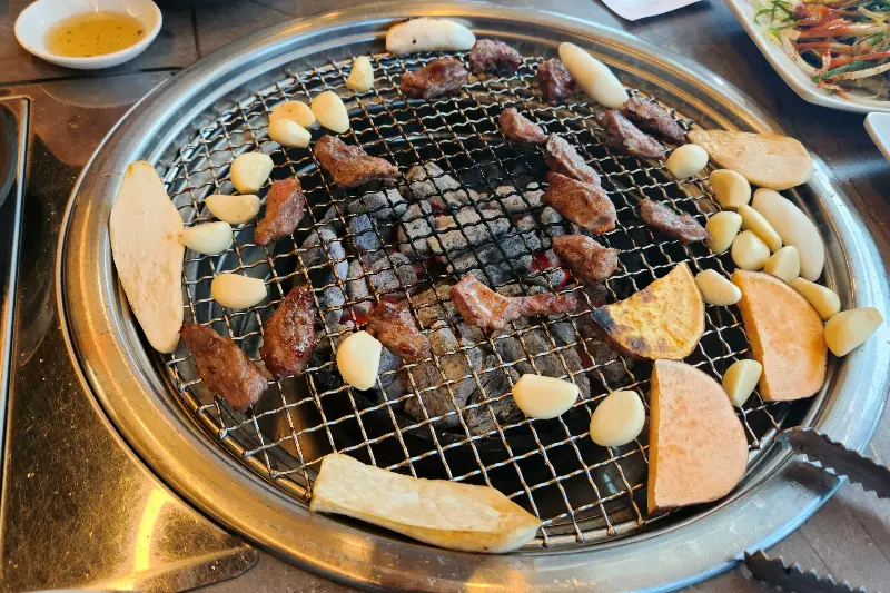 숯불 위에서 갈매기살과 함께 구워지는 떡과 마늘