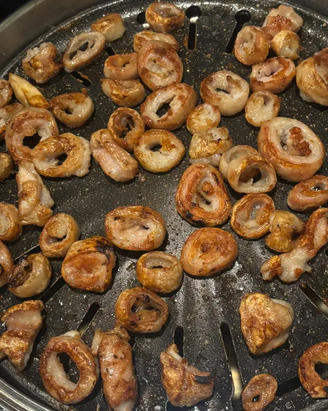 불판 위에서 맛있게 구워진 막창의 클로즈업 사진