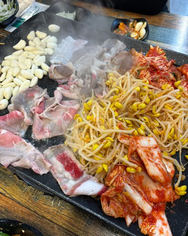 대패삼겹살과 콩나물, 김치가 함께 구워지고 있는 모습