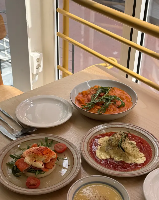 통창 옆 테이블에 놓인 에그 베네딕트, 로제 수제비, 샐러드