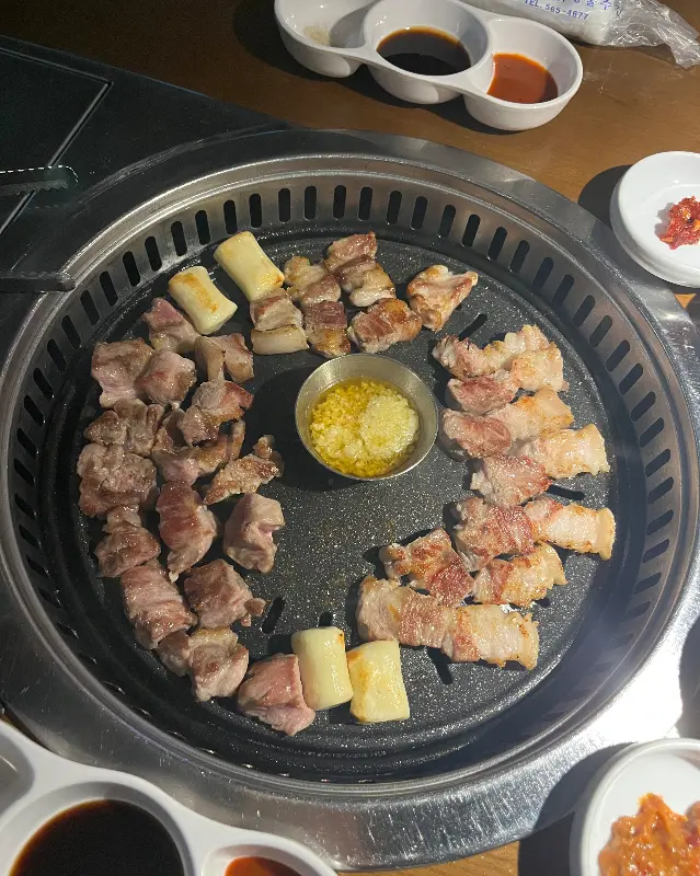 불판 위에서 맛있게 익어가는 삼겹살과 떡