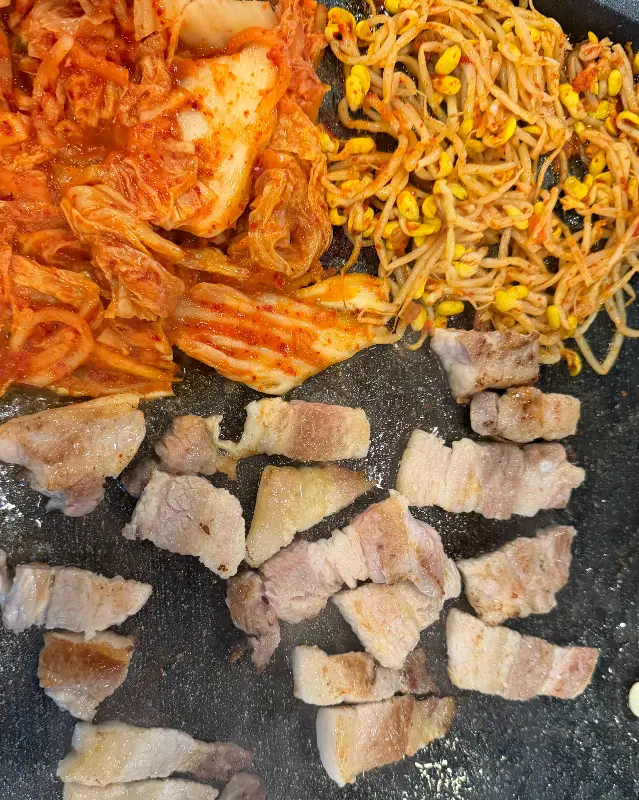 잘 익은 삼겹살 옆에서 함께 구워지는 김치와 콩나물