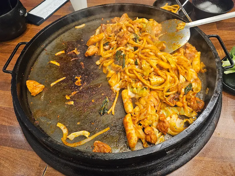 닭갈비와 우동사리가 함께 볶아진 모습. 우동 면발에 붉은 양념이 골고루 배어들어 더욱 먹음직스럽다.