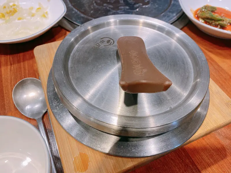 솥밥 뚜껑이 닫힌 채로 테이블에 놓여 있는 모습