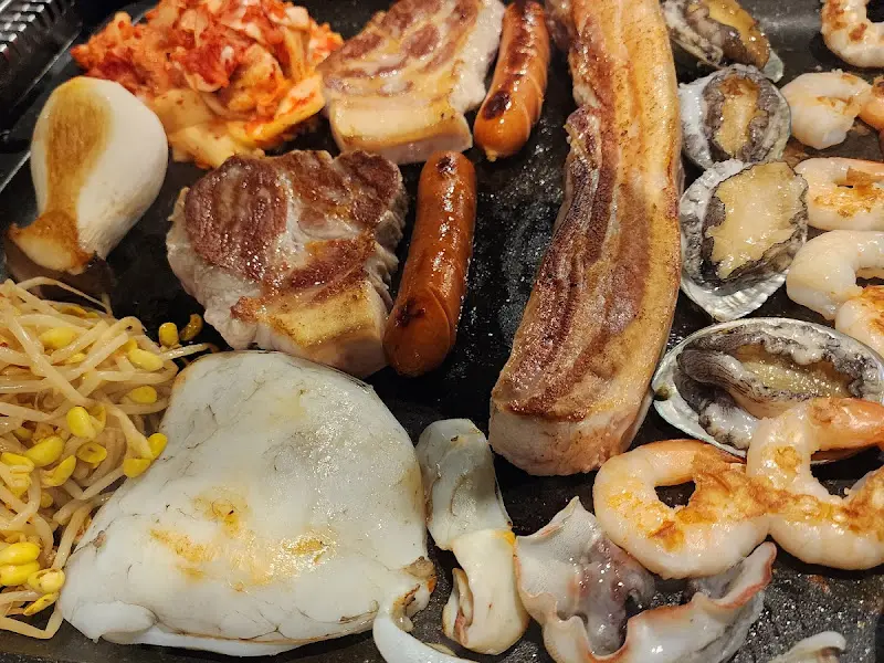 불판 가득 채워진 흑돼지, 새우, 전복, 김치