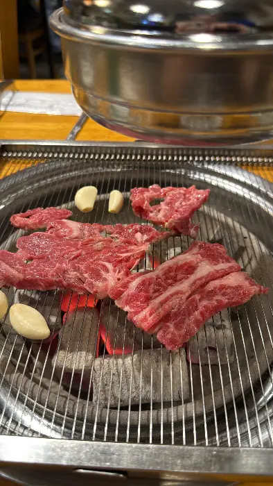 숯불 위에 신선한 갈비와 마늘이 올려져 구워지고 있습니다.