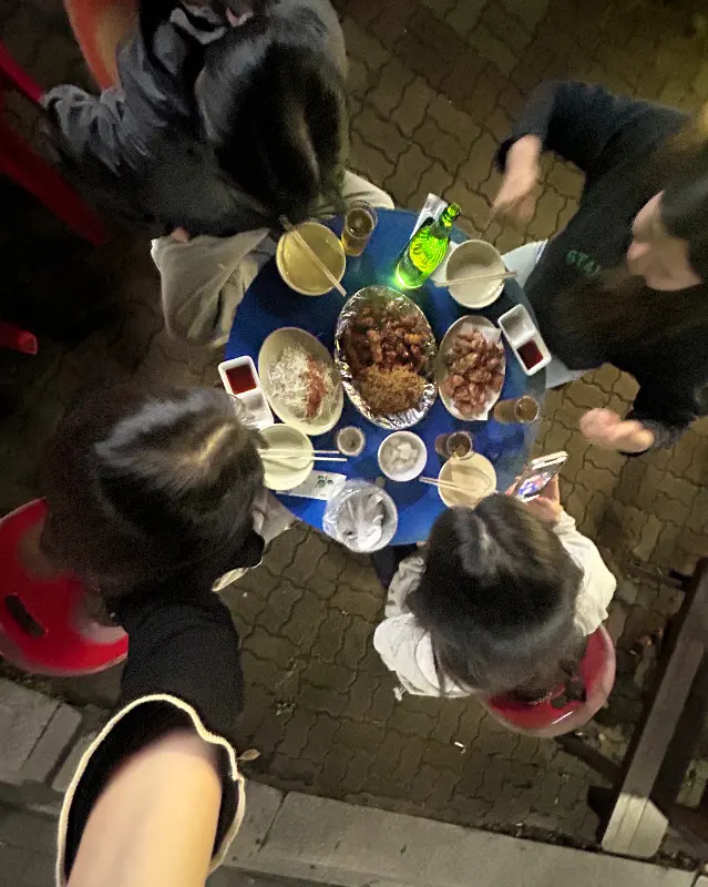 둥근 테이블에 둘러앉아 꼬꼬아찌 치킨을 즐기는 사람들