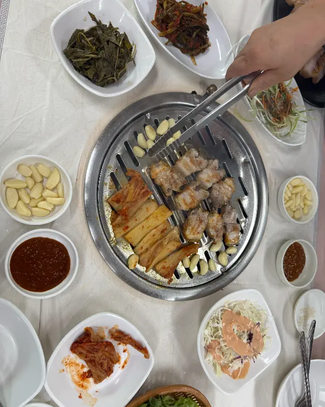 불판 가득 올라간 돼지고기와 김치, 마늘의 조화