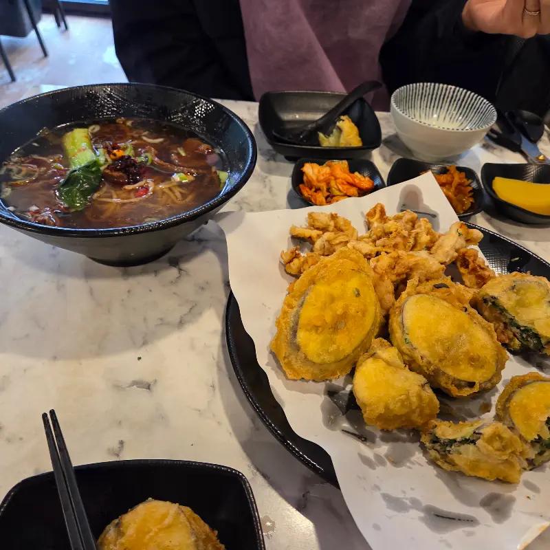 테이블 위에 놓인 우육면과 반반 튀김, 그리고 다양한 밑반찬들의 모습. 정갈하게 담겨 나온 반찬들이 눈길을 끈다.