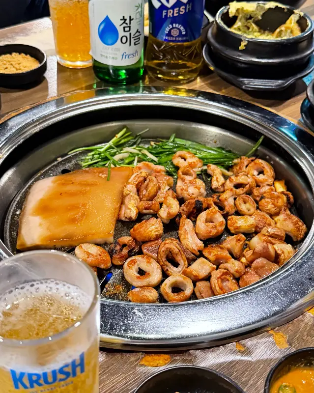 불판 위의 막창 옆에 맥주와 소주 병이 나란히 놓여 있는 모습