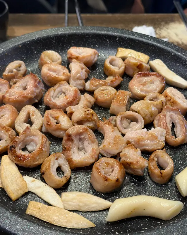 불판 위에서 맛있게 구워진 막창과 떡의 모습