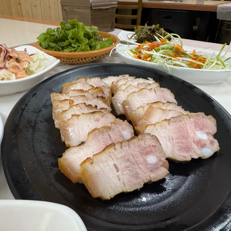 초벌 돼지고기와 다채로운 밑반찬이 정갈하게 차려진 모습