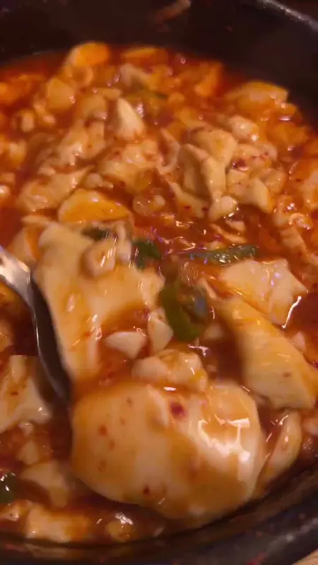 숟가락으로 순두부를 뜨는 모습 클로즈업 사진.