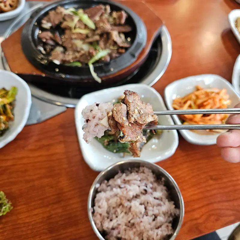 돼지불고기를 젓가락으로 집어 밥 위에 올린 모습