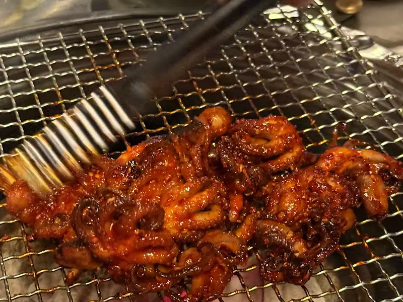 맛있게 구워진 쭈꾸미를 집게로 집어 올리는 모습