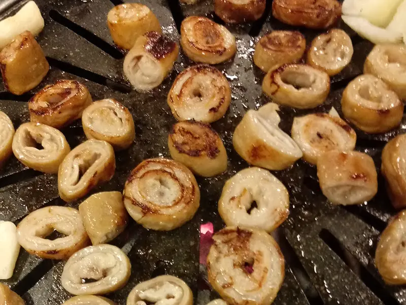 불판 위에서 노릇하게 구워지고 있는 막창의 클로즈업 모습